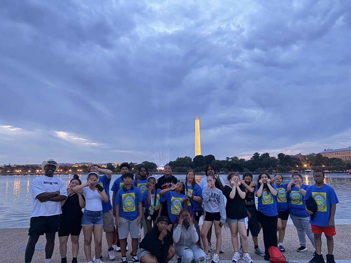 A Landmark student group at the Tidal Basin at dusk, with the Washington Monument lit behind them