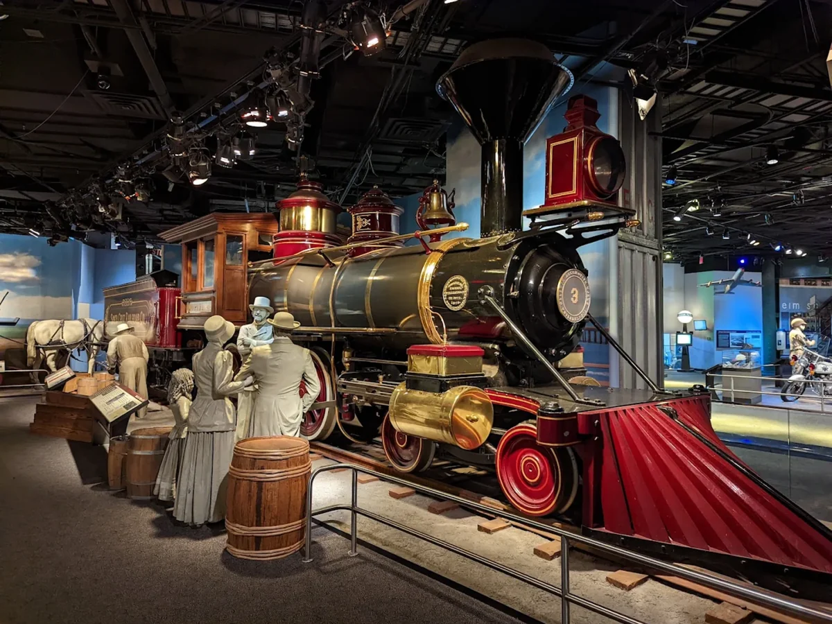 A historic steam locomotive and early aircraft in a transportation and engineering exhibit