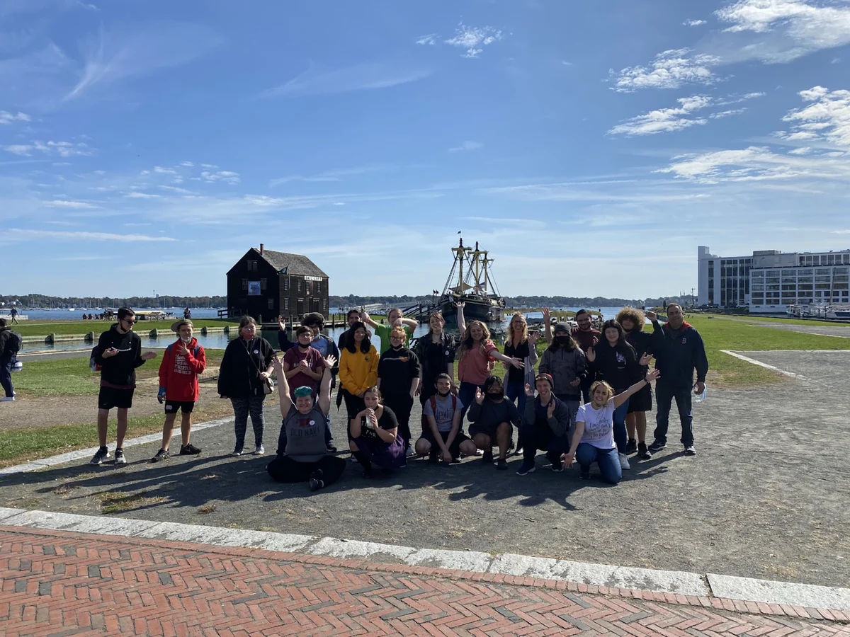 A Landmark student group beside the harbor at Salem Maritime National Historic Site in Massachusetts, with a tall ship behind them