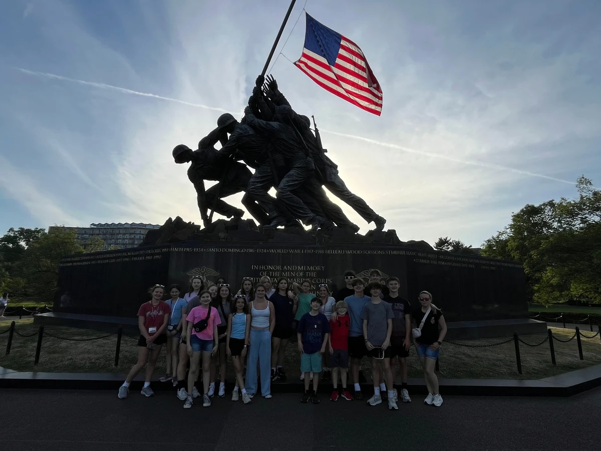 A Landmark student group at the Marine Corps War Memorial in Arlington, Virginia, with the flag flying above them