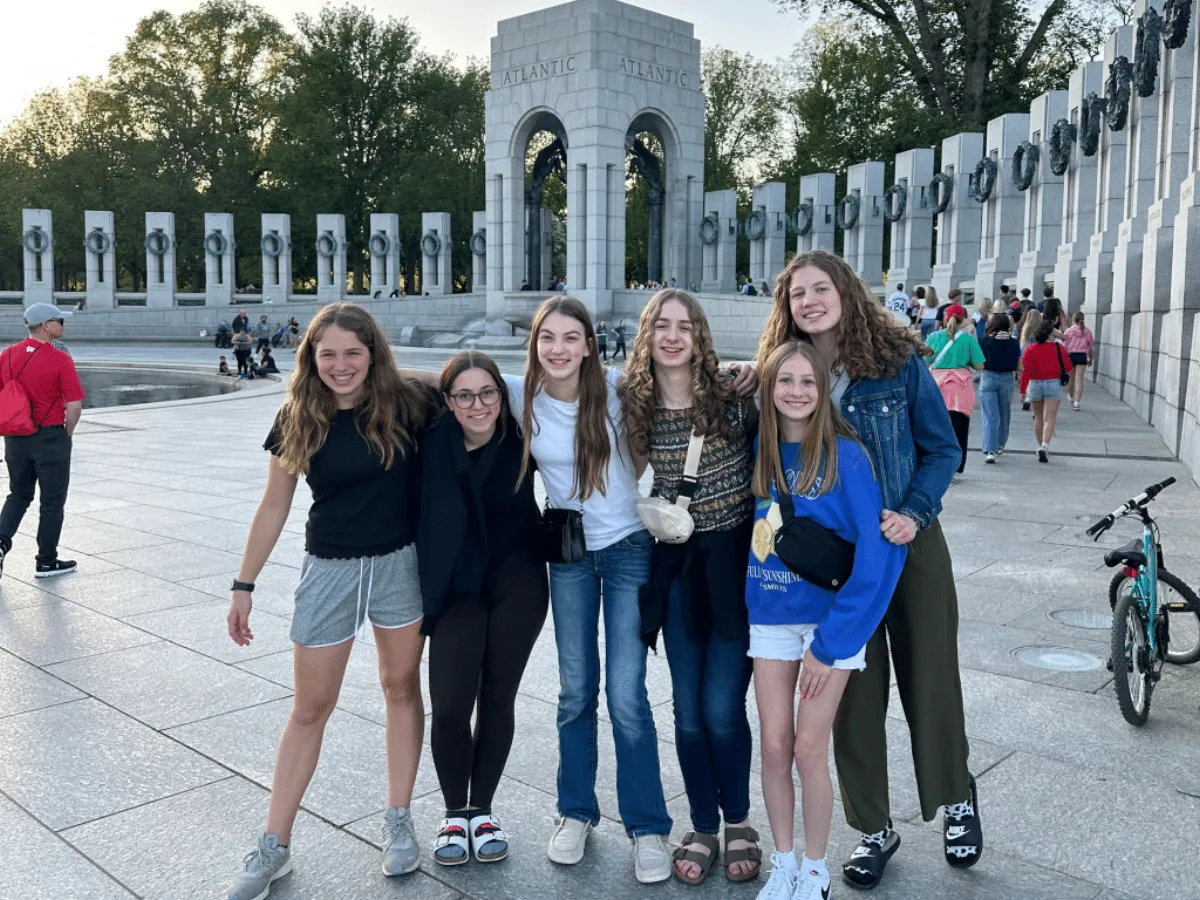 Six students standing arm in arm in front of the World War II Memorial during a Landmark Washington, DC school trip