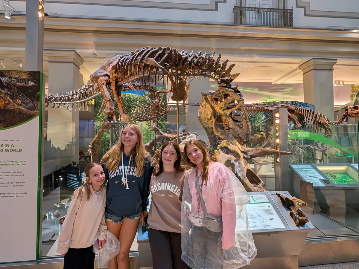 Students from a Landmark school group beside the dinosaur skeletons at the Smithsonian National Museum of Natural History in Washington, DC