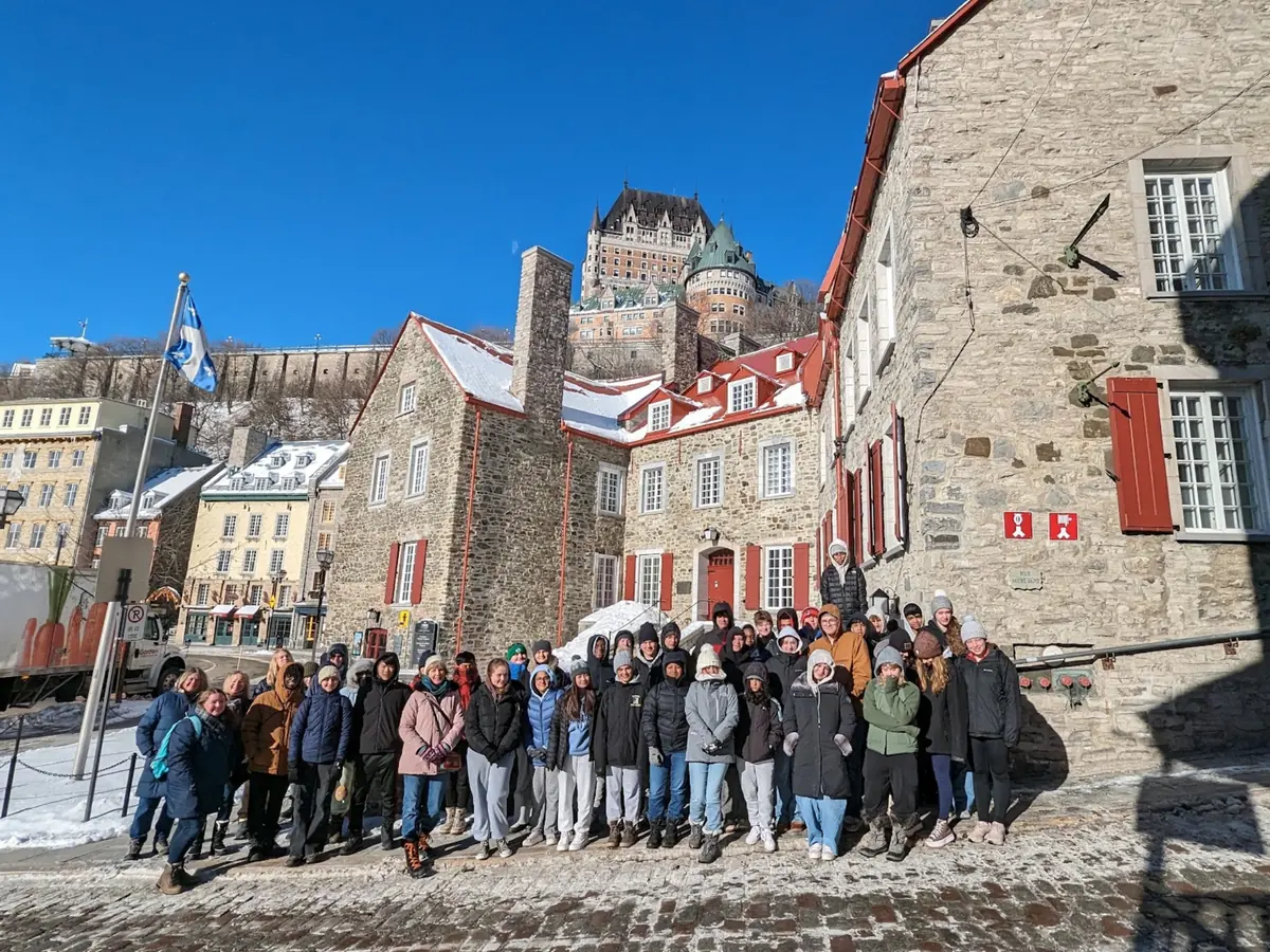 A Landmark student group in winter coats in Old Quebec, with the Château Frontenac on the hill behind them