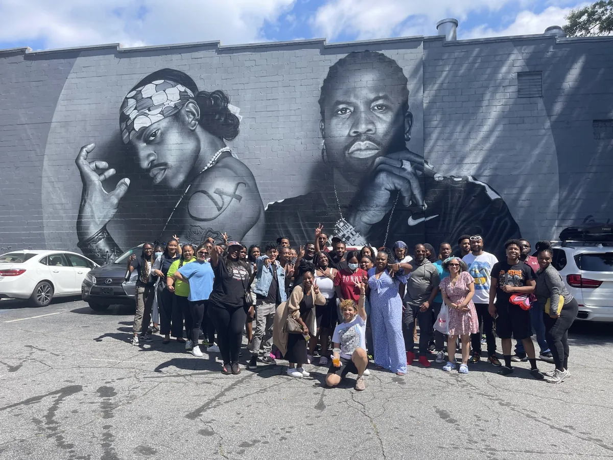 A large Landmark student group in front of a painted mural on a brick wall in Atlanta