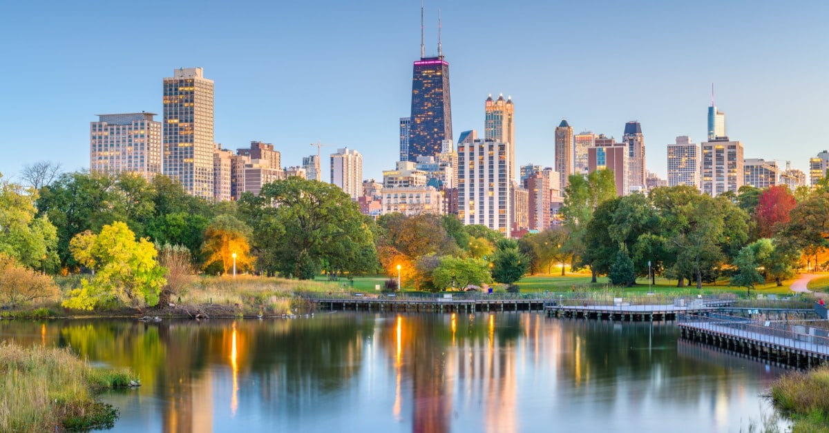 skyline view of downtown Chicago from Lincoln Park. There are full, lush trees at the bottom of the skyline.