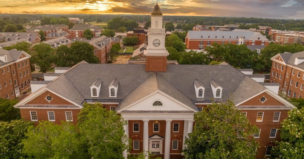 An aerial view of Virginia State University with the sun going down behind small clouds in the background.