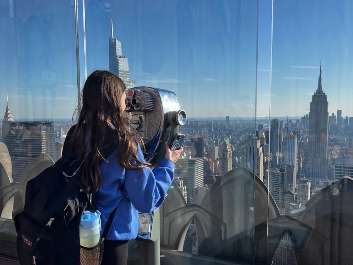A student looking out over the Manhattan skyline from an observation deck in New York City
