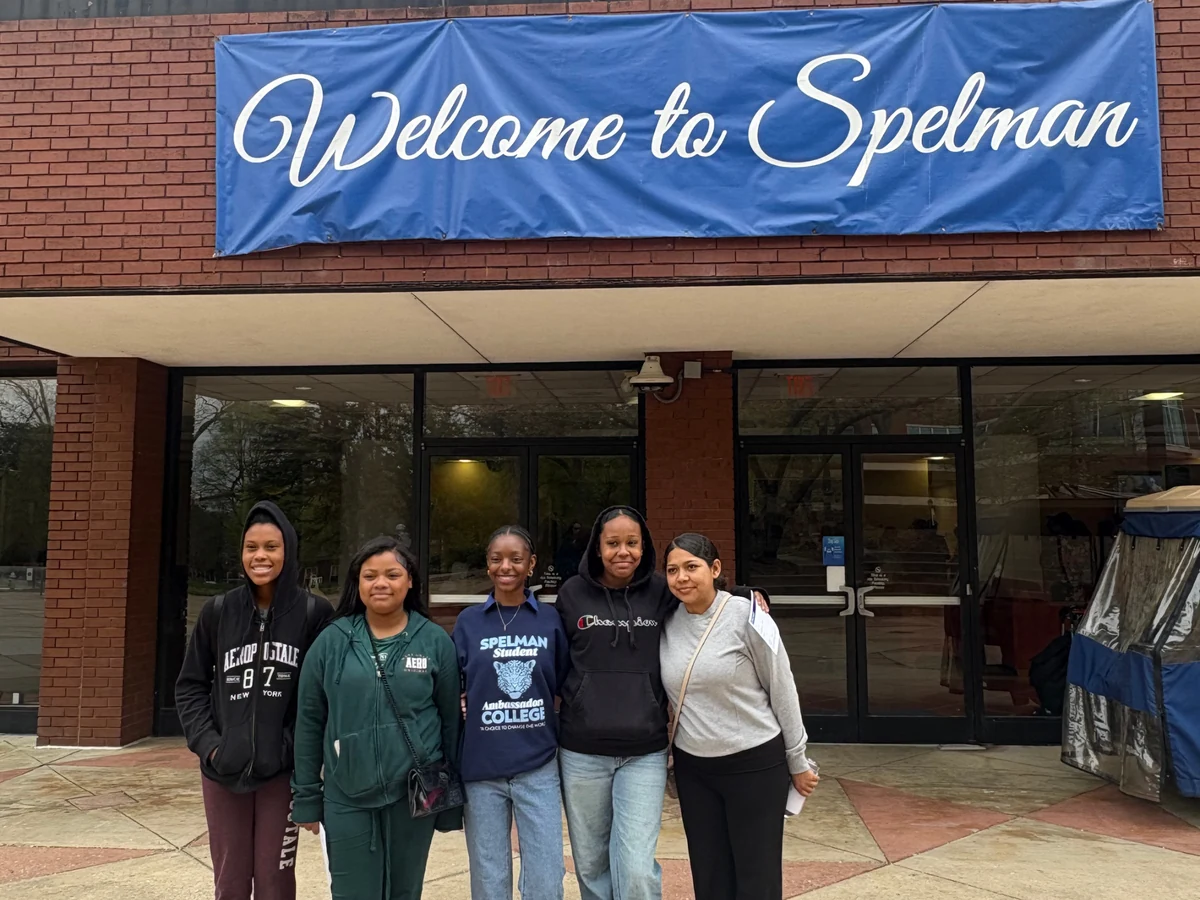 Landmark students and a chaperone outside a Welcome to Spelman banner during a college campus visit