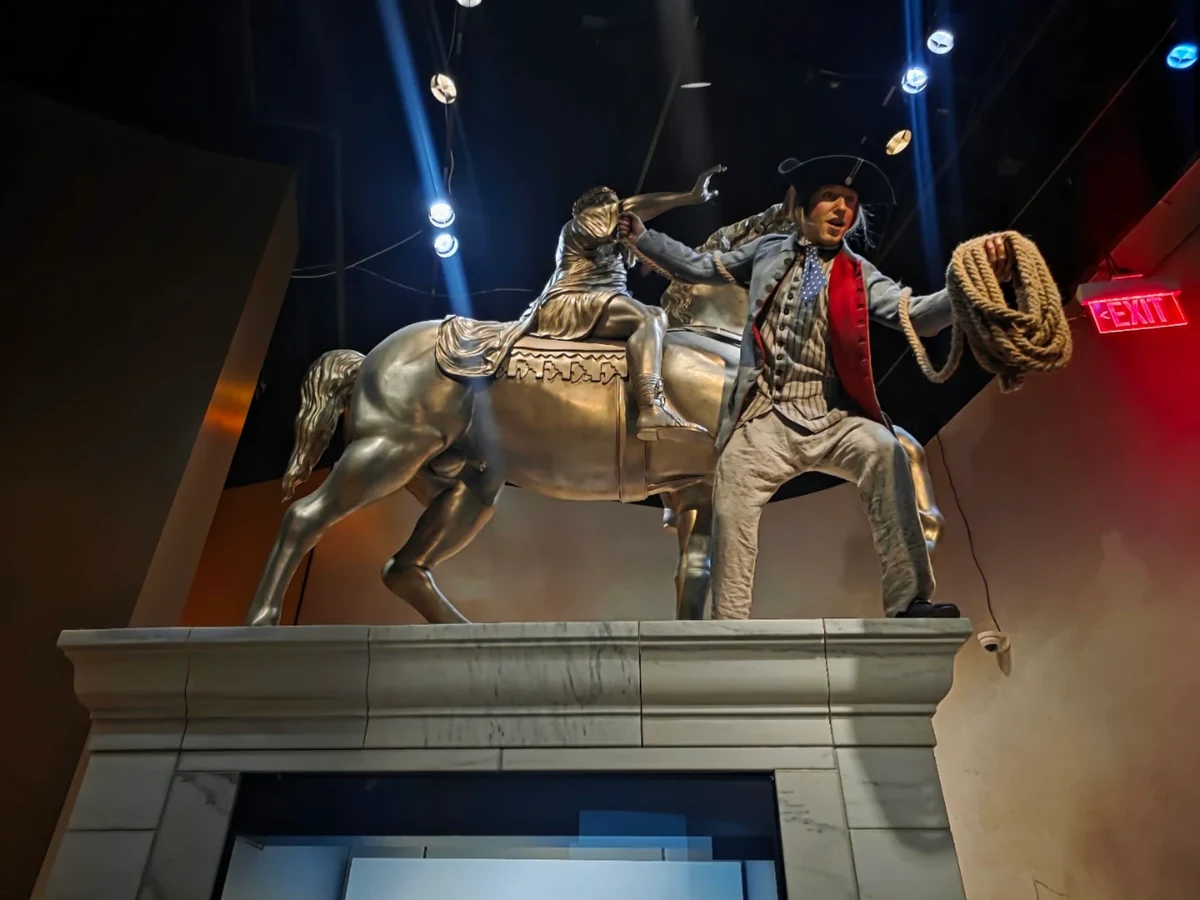 A museum tableau showing a colonist with rope preparing to topple an equestrian statue of King George III