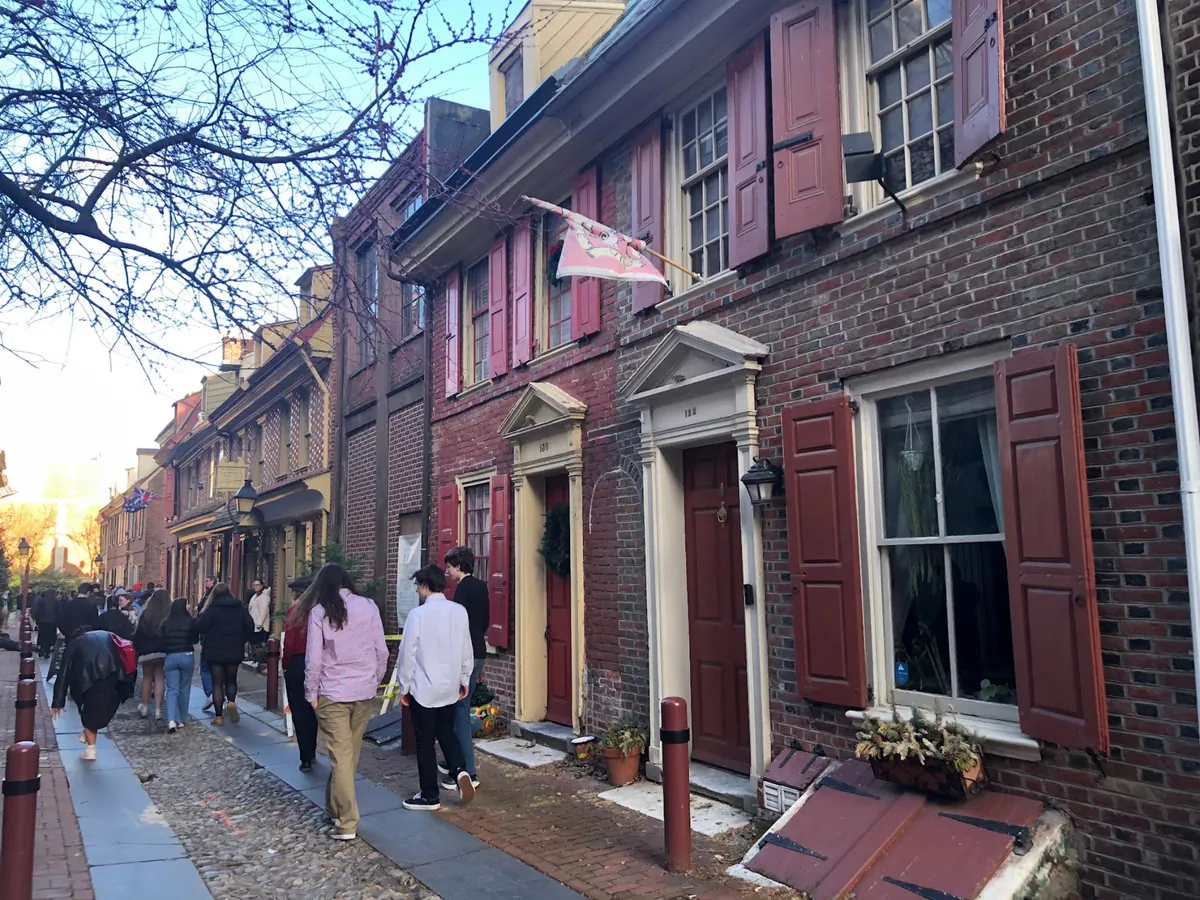 Students walking along the cobblestones of Elfreth's Alley past eighteenth-century brick houses