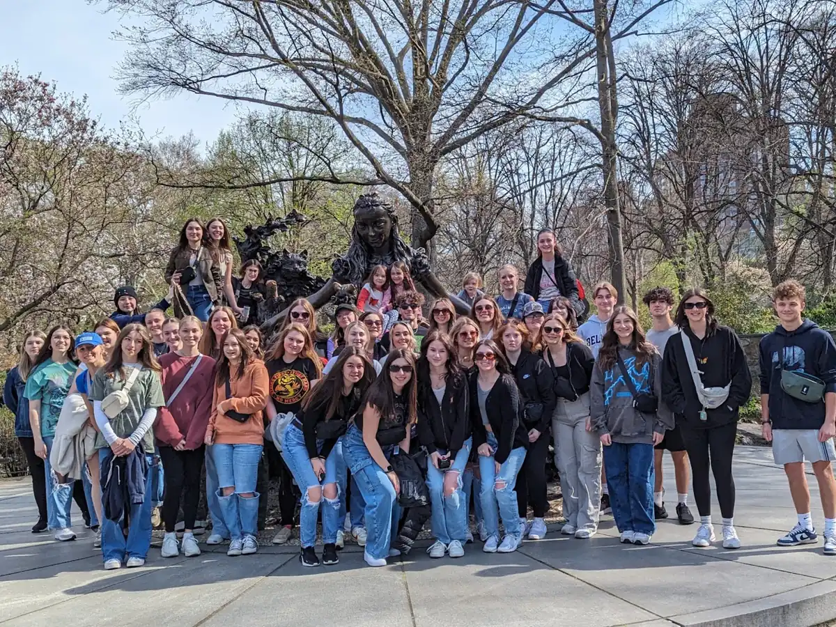 A large Landmark high school group photographed beside the Alice in Wonderland statue in Central Park, New York City