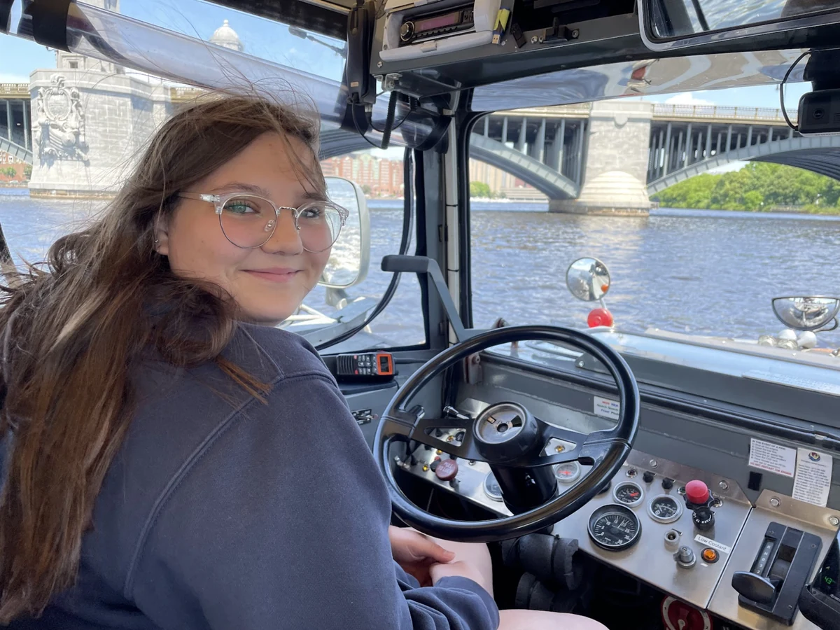 A Landmark student taking a turn at the wheel of a Boston Duck Tour boat on the Charles River