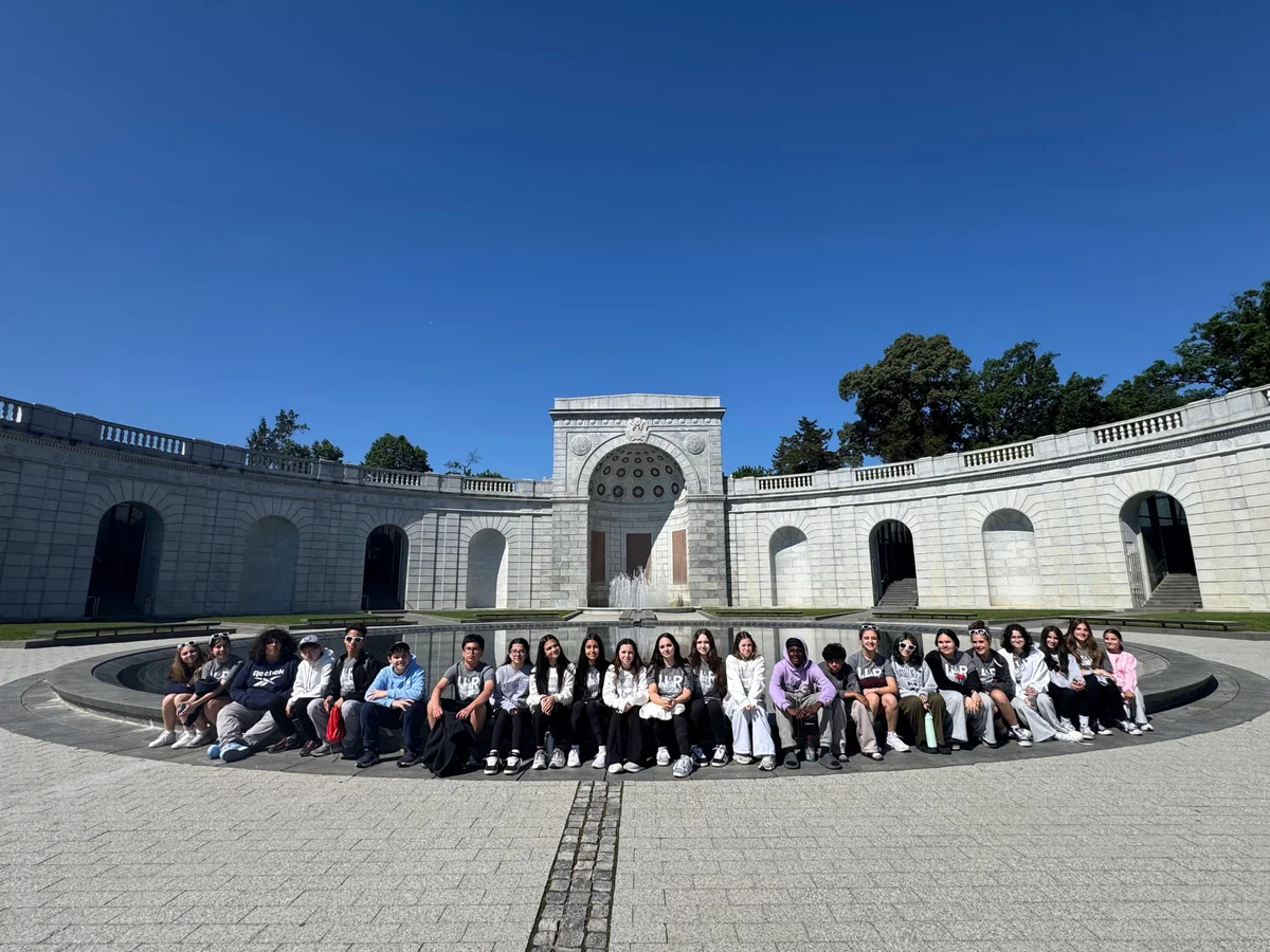 A Landmark student group seated along the reflecting pool at the Women in Military Service for America Memorial at Arlington National Cemetery