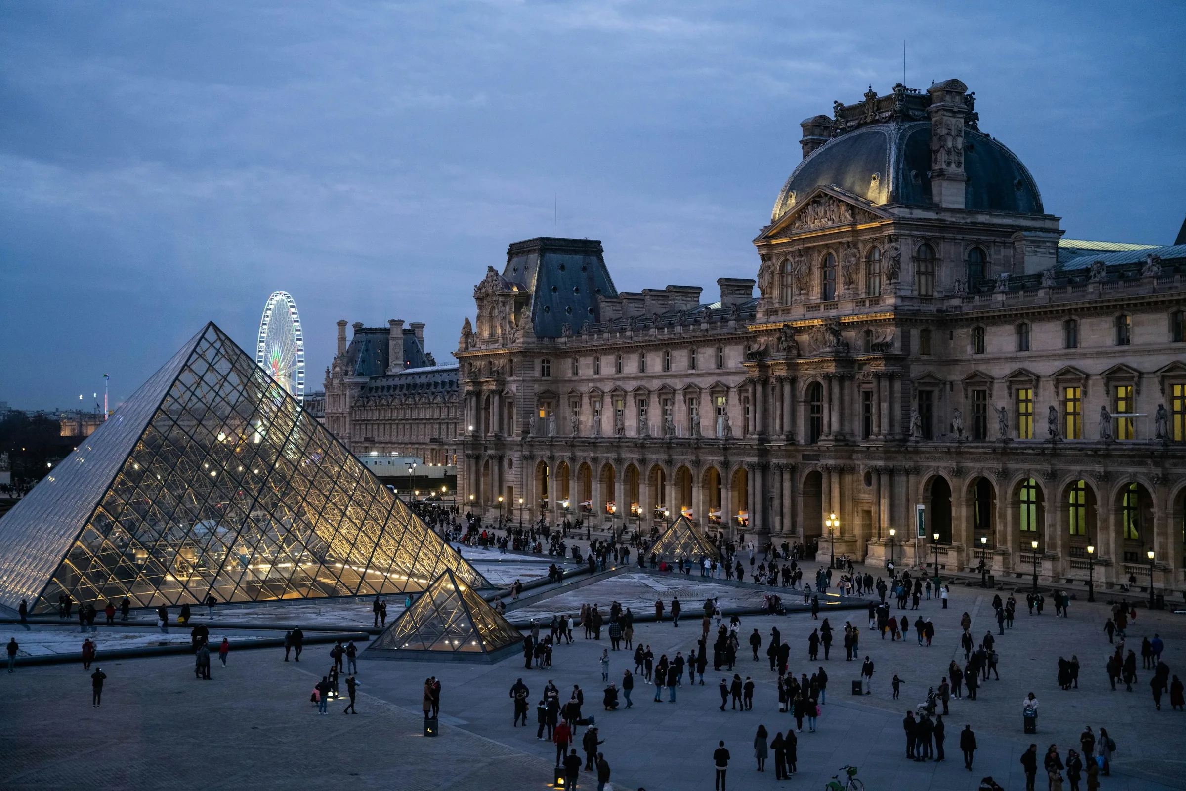 The glass pyramid and courtyard of the Louvre Museum in Paris at dusk