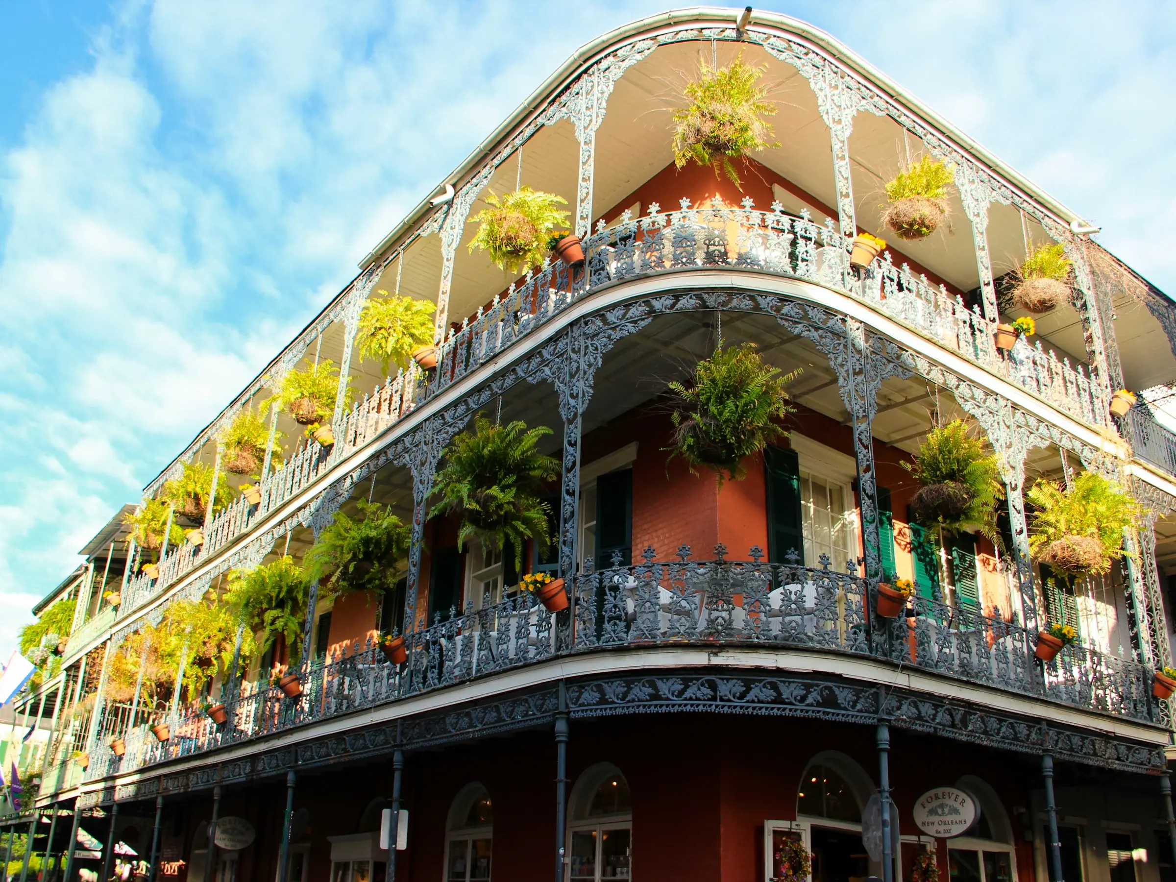 Wrought-iron balconies hung with ferns on a French Quarter corner in New Orleans
