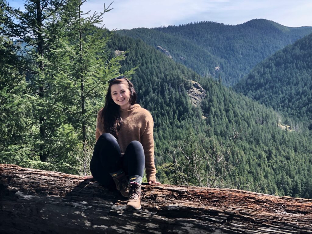 Student traveling in Oregon with tree background.