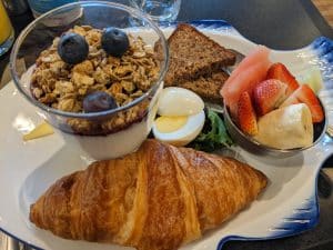 continental breakfast with yogurt, a croissant, fruit and a boiled egg.