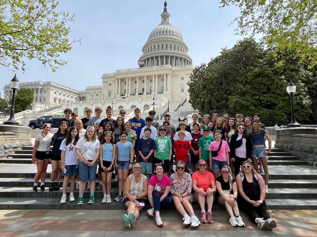A group of people posing for a photo in front of a white building.