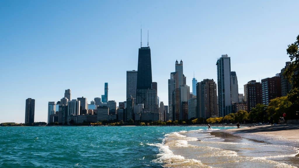 Chicago skyline with tall buildings along Lake Michigan, viewed from the lakeshore on a sunny day with gentle waves and a clear blue sky—perfect scenery for a memorable Chicago Field Trip.