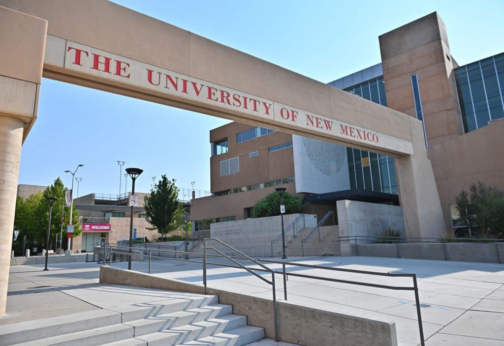 A large archway with red text reading “The University of New Mexico” stands in front of modern campus buildings and stairs on a sunny day, making it a memorable stop for any Los Angeles School Trip exploring top universities.