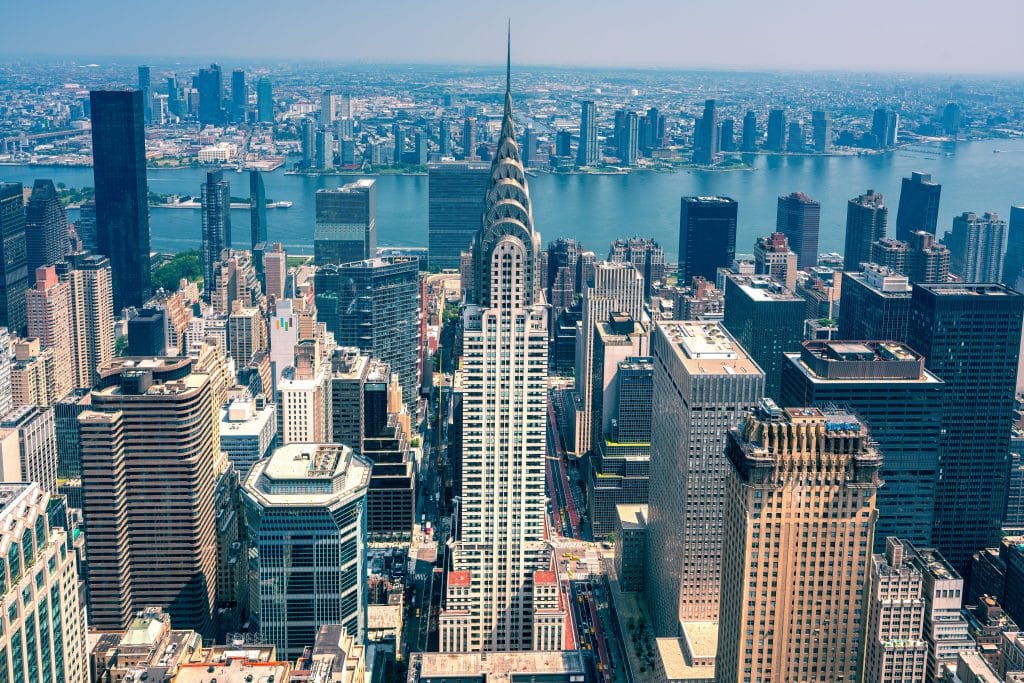 Aerial view of midtown Manhattan, New York City, featuring the iconic Chrysler Building in the foreground—an inspiring sight often enjoyed during school field trips to NYC—with the East River and Queens skyline visible in the background on a clear day.