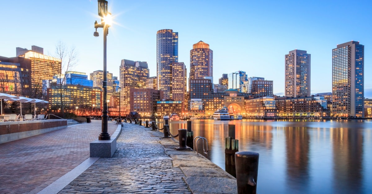 A night in Boston along the Boston Harbor looking onward at financial district. The buildings have lights on.