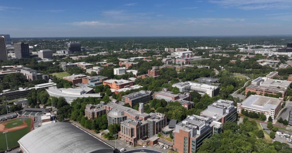 An aerial view of Atlanta during the daytime. There are buildings and a college campus scattered around town.