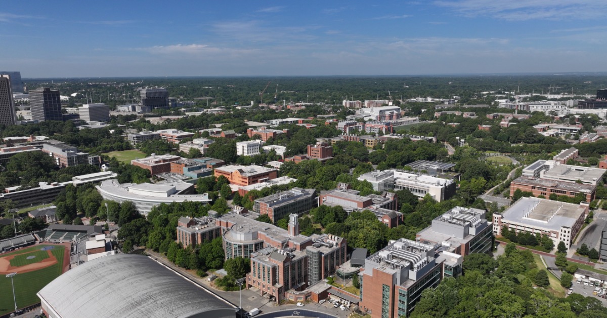An aerial view of Atlanta during the daytime. There are buildings and a college campus scattered around town.
