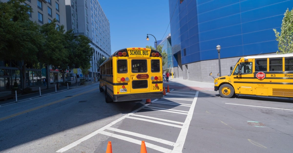 Two Atlanta school buses drive around the corner in downtown Atlanta. They drive by a museum and aquarium.