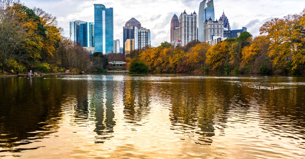 A view of the downtown Atlanta skyline from a waterway. The sun is going down and the leaves are turning for fall.