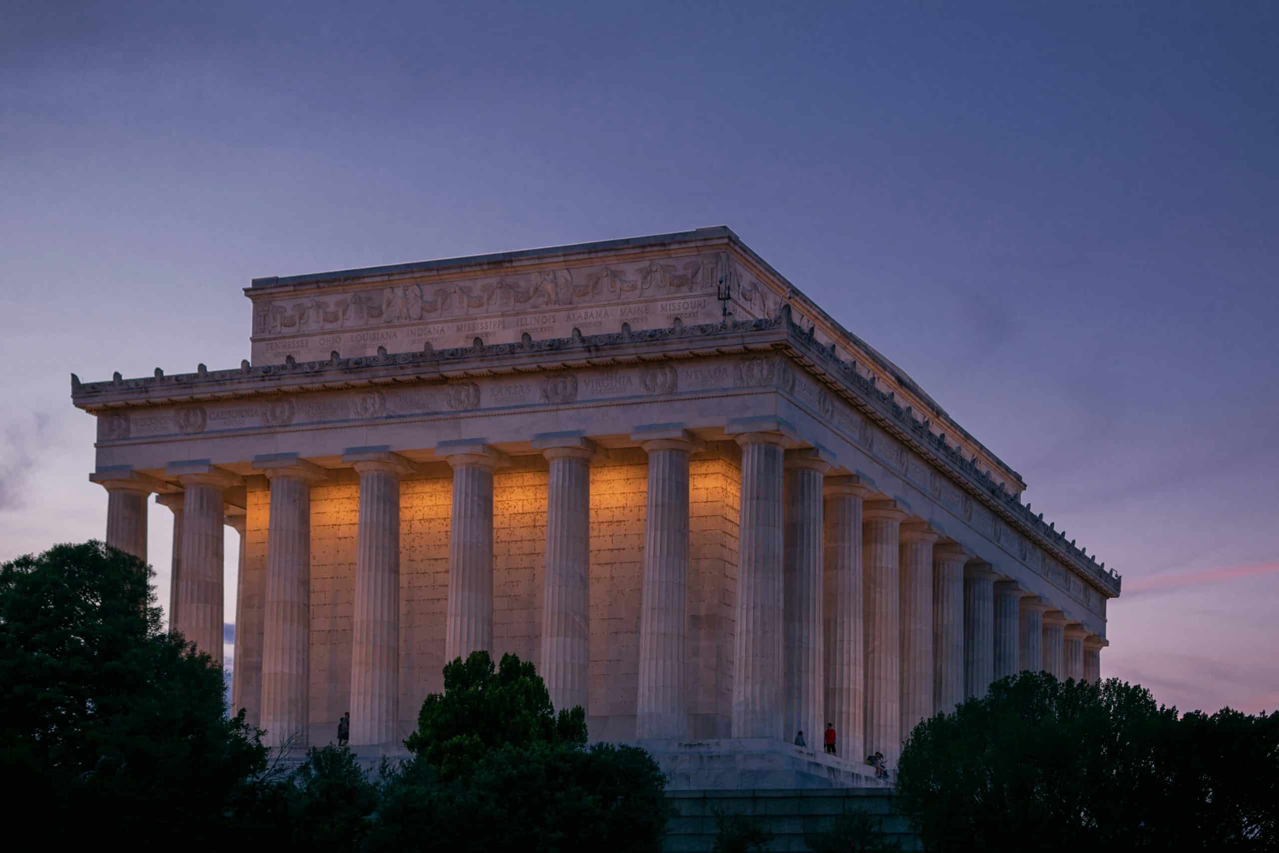 The Lincoln Memorial in Washington, D.C., is illuminated at dusk, its iconic columns glowing beneath a purple and blue evening sky—a must-see for anyone following Student Travel Trends for 2027.