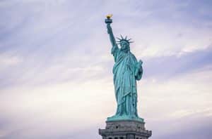 The Statue of Liberty stands tall against a cloudy sky, holding a torch in her right hand and a tablet in her left—an inspiring sight for Field Trips NYC, symbolizing freedom and hope.