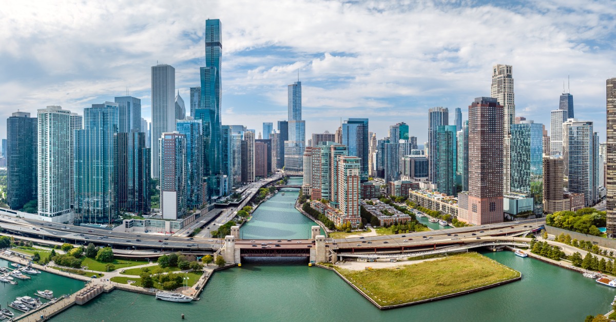 An aerial view of downtown Chicago on a sunny summer day. The river is in the center and leads to the lake.