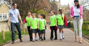 A group of six students wear matching hi-vis safety shirts as they walk in a group with two chaperones.